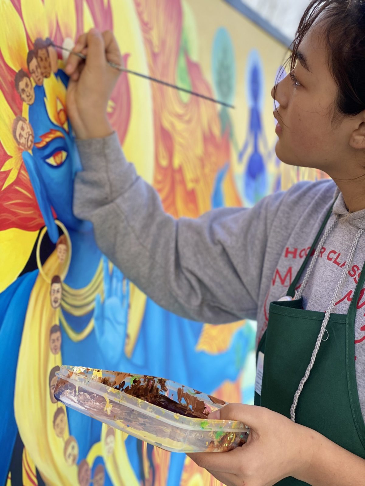 An artist adds detail to a colorful mural with a tiny paintbrush.